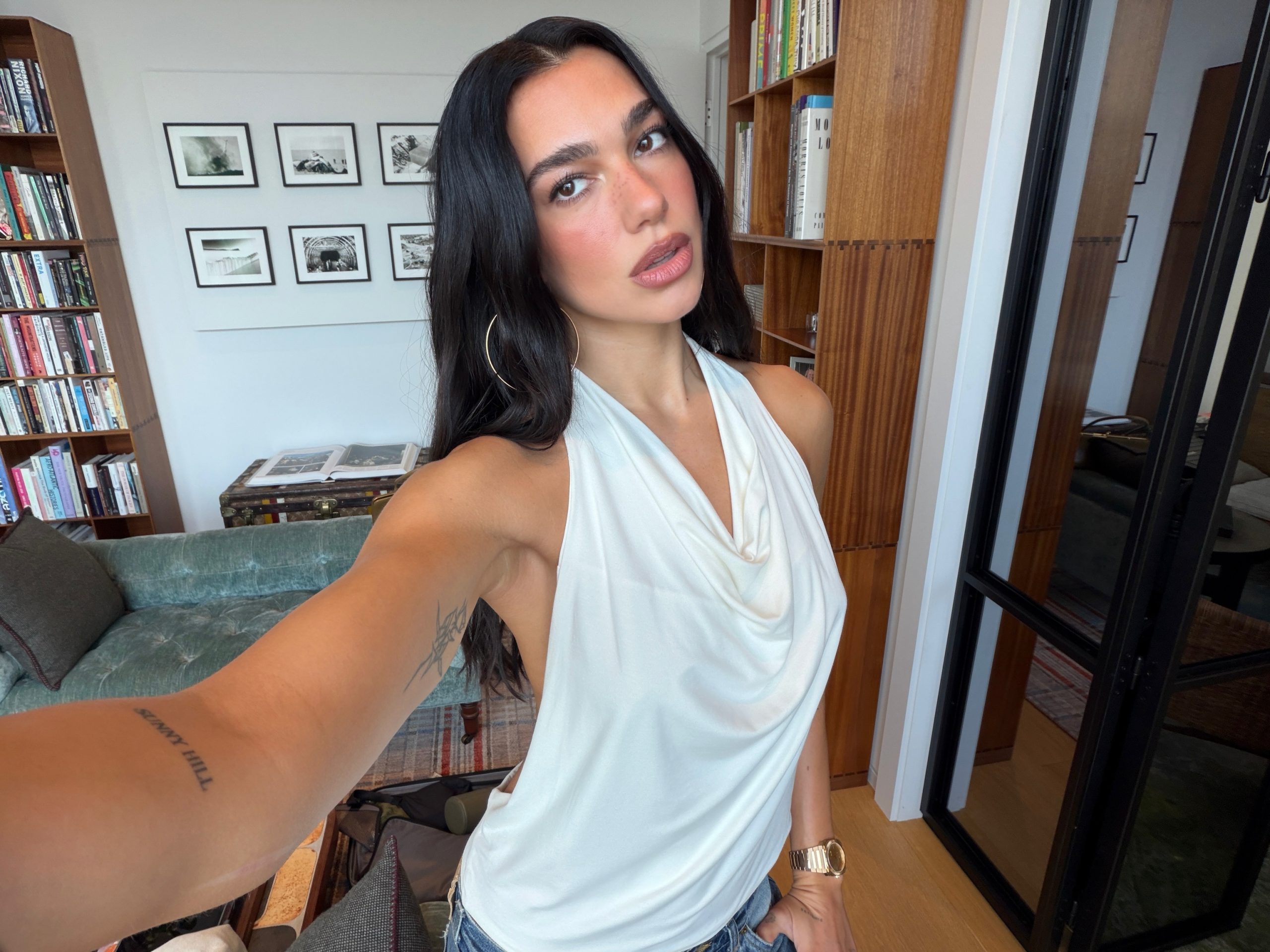 Η Dua Lipa με λευκό draped halter τοπ, χρυσούς κρίκους και τζιν.