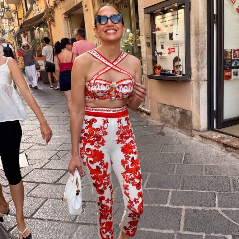 H Jennifer Lopez με λευκό και κόκκινο εμπριμέ σύνολο, λευκή τσάντα και γυαλιά ηλίου.