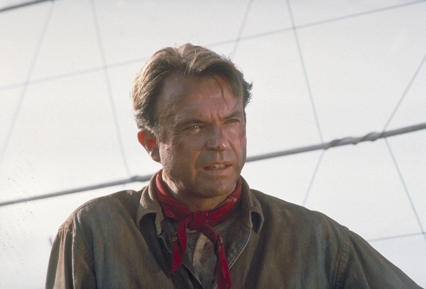 O ηθοποιός Sam Neill στο ρόλο του Dr. Alan Grant, δίπλα σε έναν ηλεκτρικό φράχτη σε μια σκηνή από την ταινία «Jurassic Park», 1993.