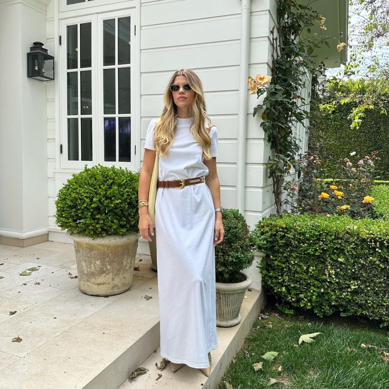 Η Sofia Richie Grainge με μάξι λευκό t-shirt φόρεμα, καφέ δερμάτινη ζώνη με χρυσή αγκράφα και μαύρα γυαλιά ηλίου.
