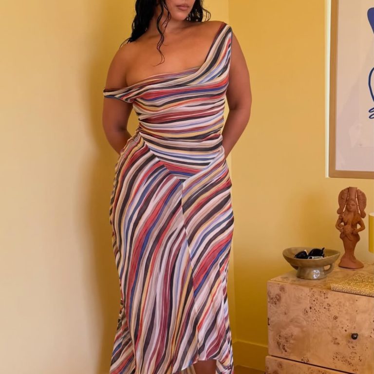 Μια γυναίκα με ένα μίντι off-the-shoulder φόρεμα σε ριγέ print με έντονα καλοκαιρινά χρώματα.