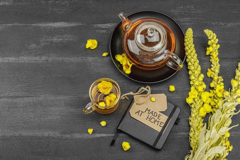 Φρέσκα άνθη φλόμου (Verbascum) πάνω σε μαύρη ξύλινη επιφάνεια και αφέψημα