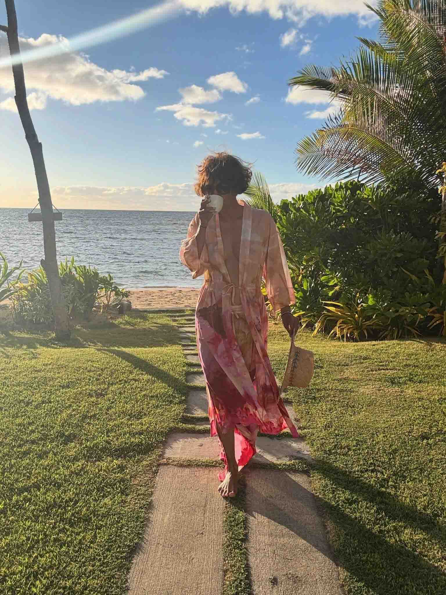 Η Halle Berry ποζάρει με φλοράλ ρόμπα σε παραθαλάσσιο προορισμό κρατώντας μια κούπα καφέ.