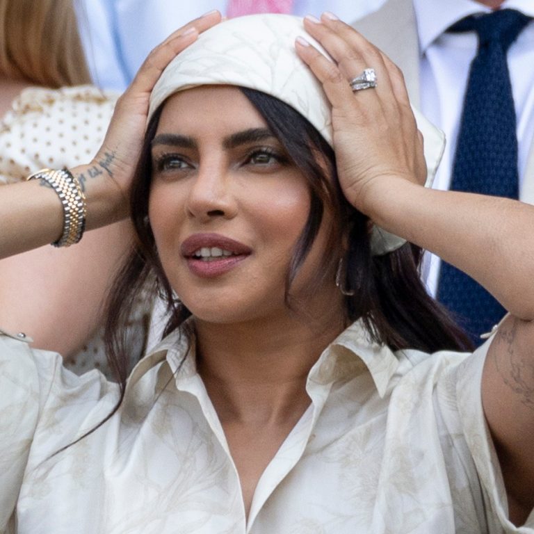 Κοντινό πλάνο της Priyanka Chopra στο Wimbledon, να φοράει κρεμ μεταξωτή μπαντάνα με φλοράλ σχέδιο στα μαλλιά, shirt φόρεμα και το Tiffany δαχτυλίδι αρραβώνων της.
