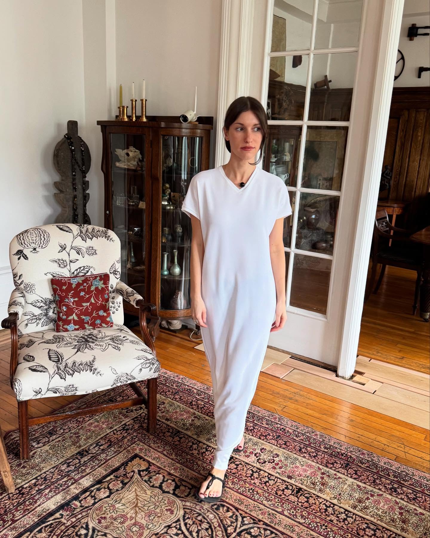 Η Laura Reilly αποδεικνύει τη δύναμη του μινιμαλισμού, συνδυάζοντας ένα λευκό μάξι t-shirt φόρεμα με V λαιμόκοψη με μαύρα φλατ σανδάλια και ένα διακριτικό choker.