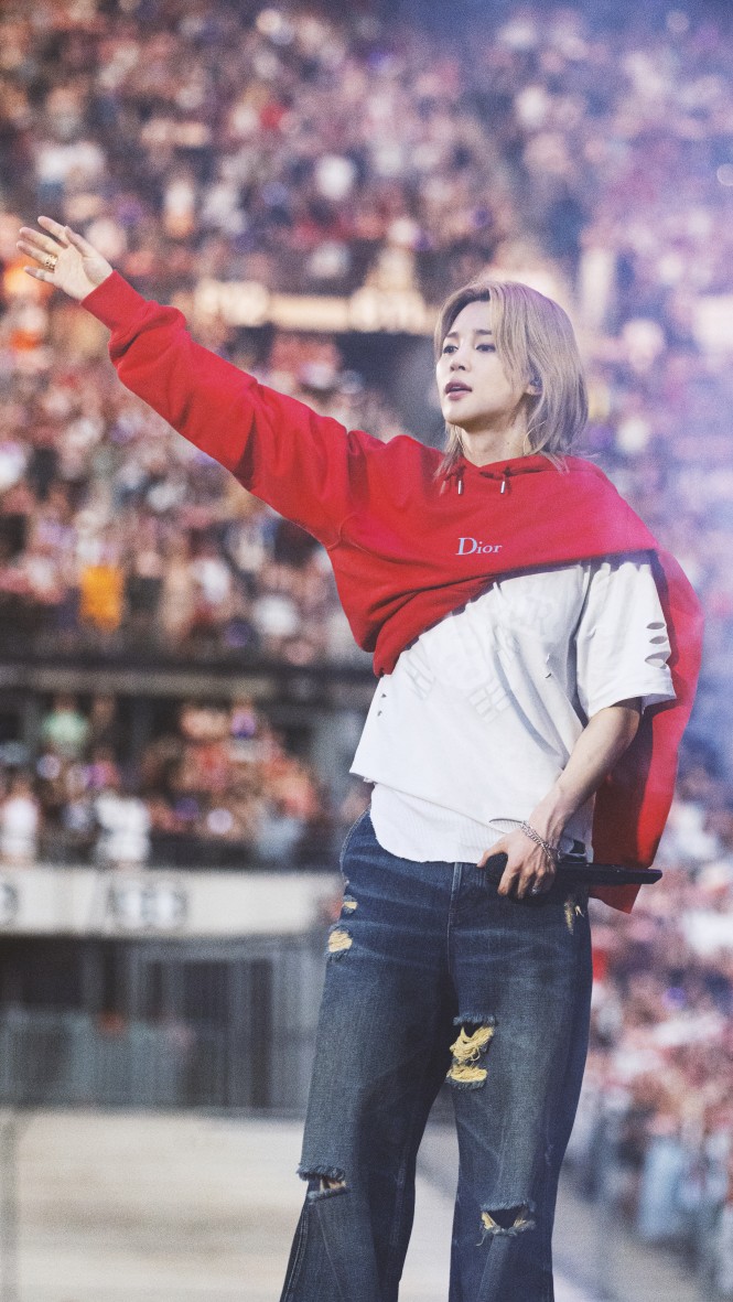 Ο Jimin με ένα πιο casual Dior look, επιλέγοντας κόκκινο βαμβακερό hoodie και μπλε denim jeans, σε μια effortless εμφάνιση με streetwear διάθεση.