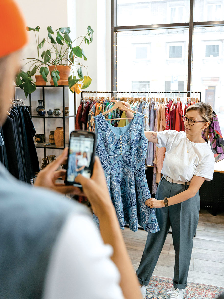 Γυναίκα που φωτογραφίζει vintage ρούχα- Vinted resale fashion trends