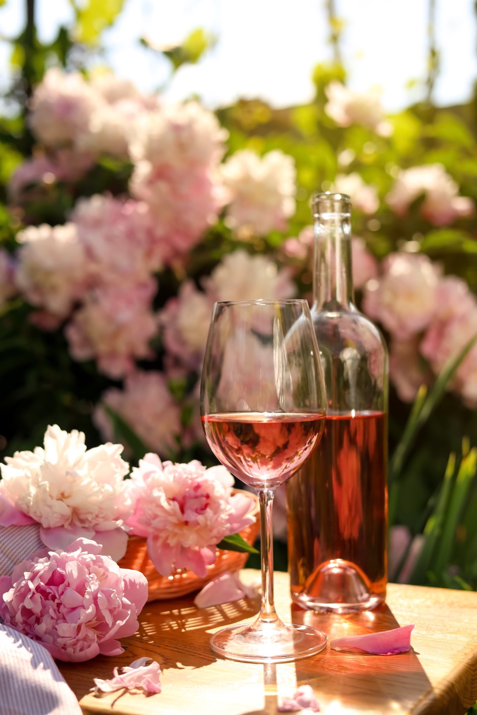 Όσο μικρότερος είναι ο χώρος με οξυγόνο μέσα στη φιάλη, τόσο περισσότερο μπορούμε να επιβραδύνουμε την οξείδωση. Στη φωτογραφία ανοικτό μπουκάλι ροζέ κρασί. Πίσω φαίνονται ροζ τριαντάφυλλα.