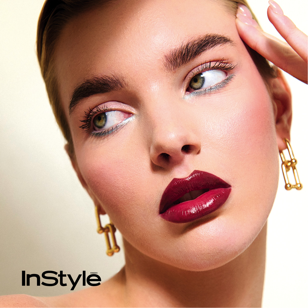 Close-up μακιγιάζ για το InStyle Greece με μπορντό κραγιόν, χρυσά σκουλαρίκια και φυσικό look στα μάτια.