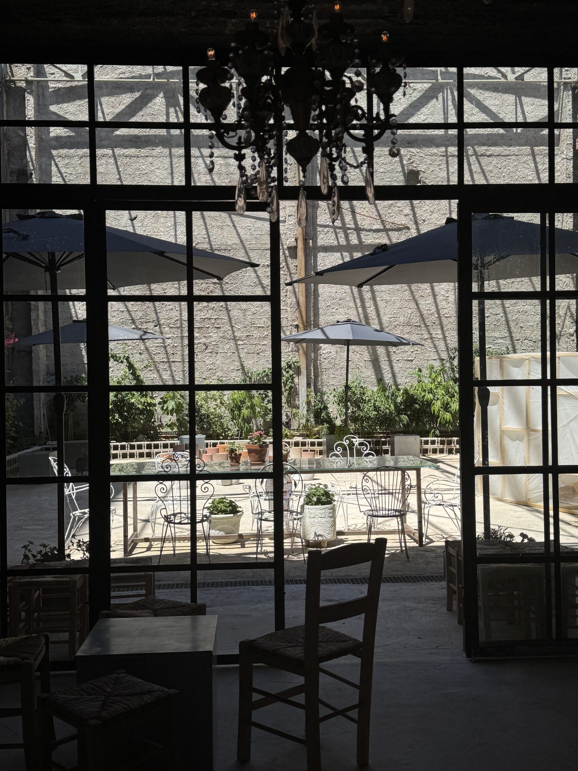 Η εσωτερική αυλή του .sympan στον Πειραιά με τραπέζια, ομπρέλες και βιομηχανική ατμόσφαιρα