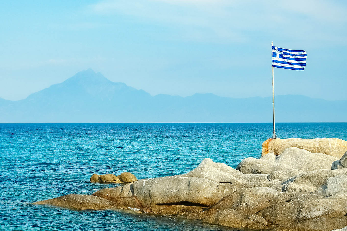 Ελληνική σημαία κυματίζει σε ακτή δίπλα στη θάλασσα