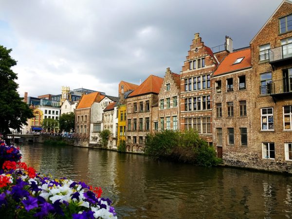 Γάνδη-Belgium-Buildings surrounded by the river and flowers under a cloudy sky in Ghent in Belgium