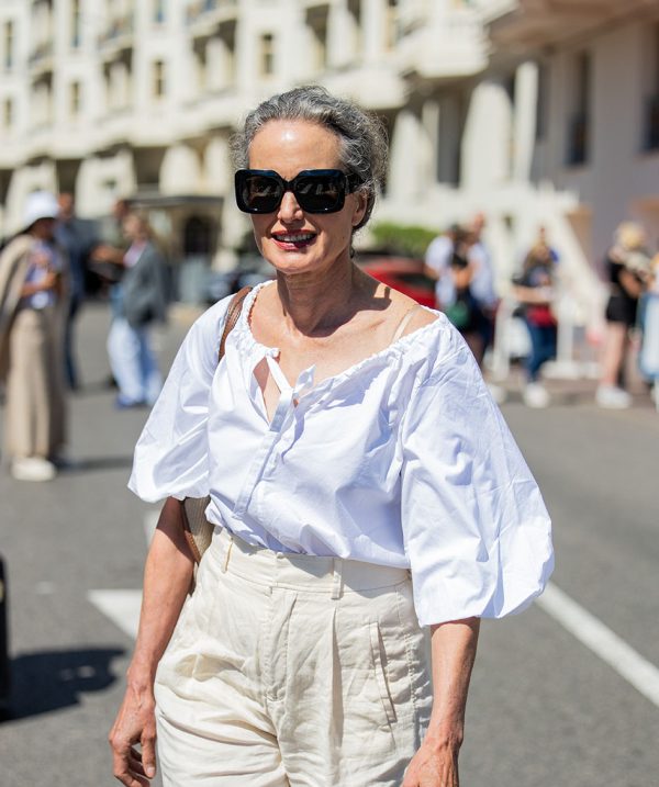 Η Andie MacDowell φορά άσπρη μπλούζα και ψηλόμεσο παντελόνι καθώς περιδιαβαίνει στους δρόμους των Καννών.