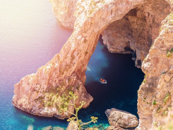 Travel-Malta-Blue Grotto in Malta. Pleasure boat with tourists runs. Natural arch window in rock
