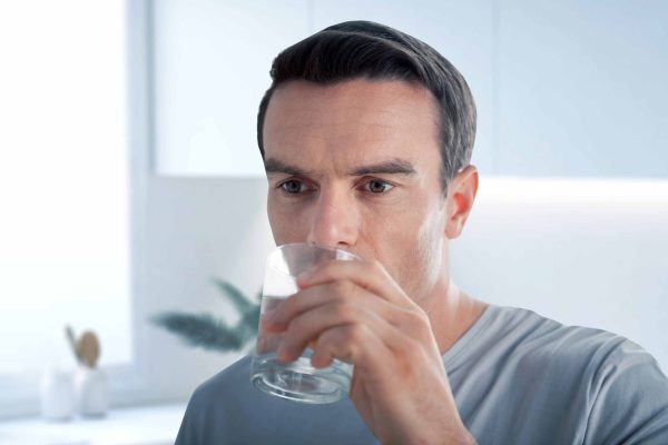 Calm man drinking water while being thirsty