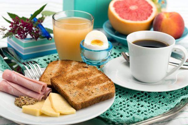 Breakfast with toast, ham, cheese, egg, grapefruit, juice and cup of coffee.