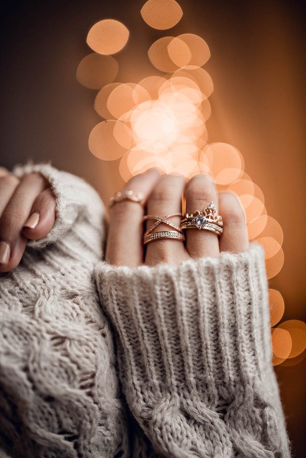 Hands with luxury rings on golden bokeh lights background