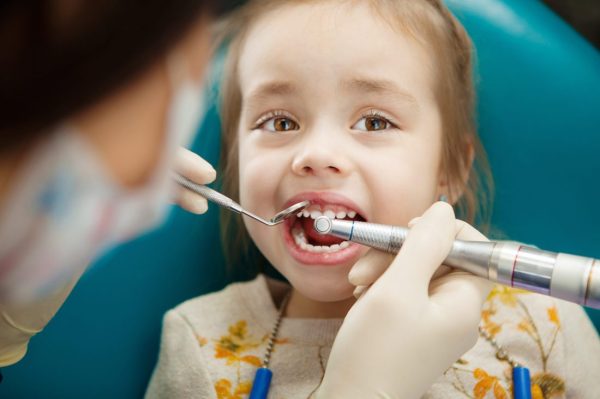 Adorable child calmly goes through procedure of teeth polishing