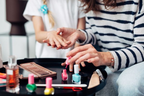 Mother and daughter doing manicure at home, painting nails with nail polish