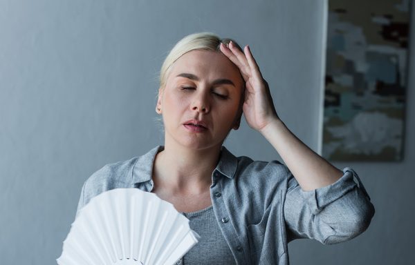 exhausted woman with menopause suffering from heat and holding f