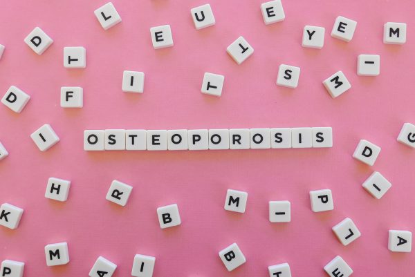Osteoporosis word made of square letter word on pink background.