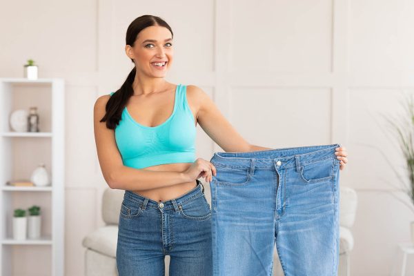 Happy Slim Woman Showing Old Oversize Jeans Standing At Home