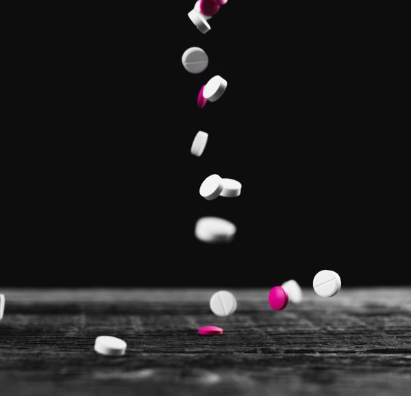 Pink and white pills fly sypyatsya on a wooden table on a black background