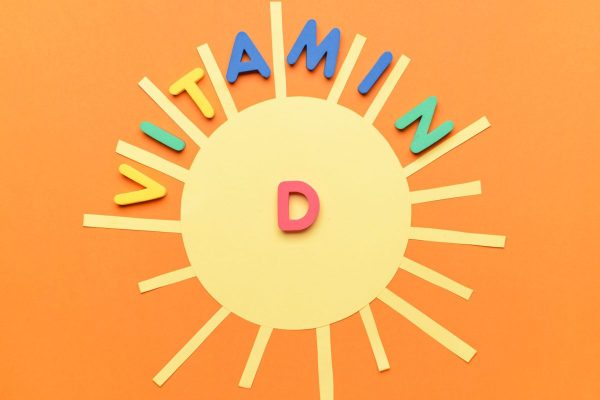 Text VITAMIN D with sun on color background