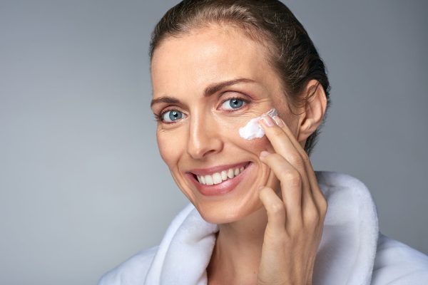 Middle age woman applying face moisturiser