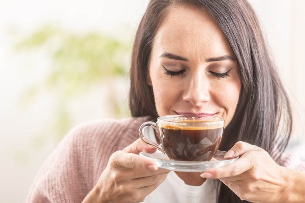 Beautiful girl enjoys the smell of freshly made coffee.