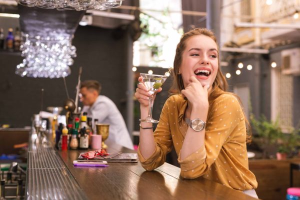 Positive young woman laughing while sitting in the bar