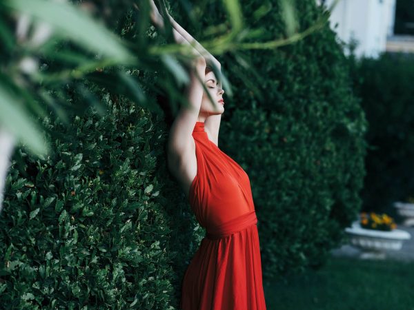 woman near bush in red dress and fairy garden decoration