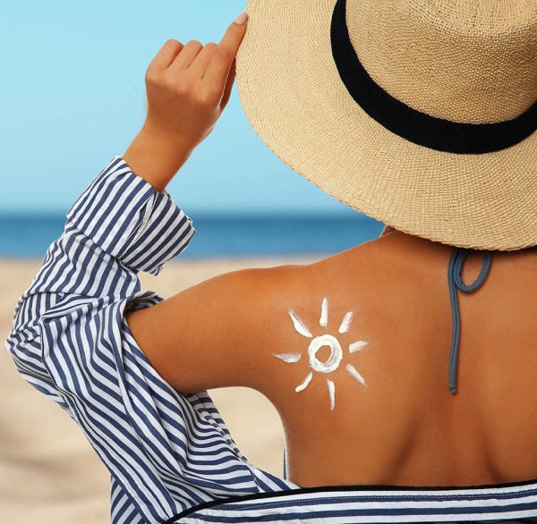 Teenage girl with sun protection cream on her back against white